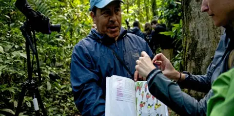Guide showing a bird book to visitors on a Monteverde Cloud Forest Reserve tour